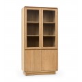 Luxusní moderní masivní knihovna Riga s vrchními skleněnými dvířky a spodními plnými dvířky z teakového dřeva v naturální světle hnědé barvě s policemi a obdélníkovou podstavou se zaoblenými rohy a vertikálním lineárním reliéfem