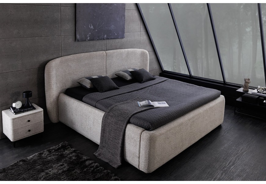 Stylová designová čalouněná postel v art deco stylu s buklé potahem v šedé barvě se širokým oblým čelem a výklopným roštem s prostorným úložným prostorem