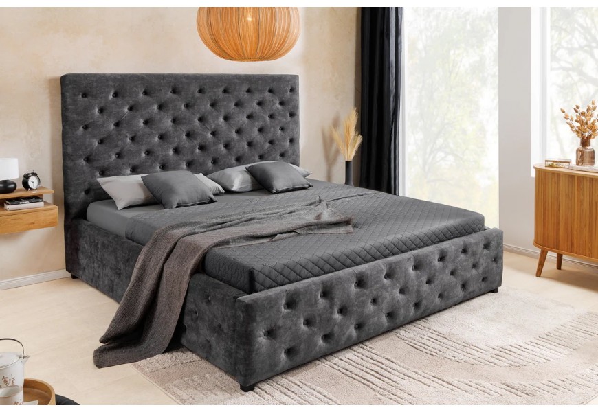Designová chesterfield manželská postel Kreon s obdélníkovým čelem a plnou základnou s úložným prostorem s nízkými nožičkami s potahem ze sametu v tmavě šedé barvě s prošíváním s kulatými knoflíčky