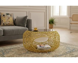 Modern&iacute; glamour konferenčn&iacute; stolek Hoja s černou tvrzenou skleněnou deskou a v&yacute;raznou zlatou kovovou podnož&iacute; s pr&aacute;&scaron;kov&yacute;m n&aacute;střikem a s odkl&aacute;dac&iacute;m prostorem se dvěma otvory