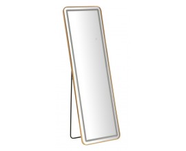 Designov&eacute; art deco obd&eacute;ln&iacute;kov&eacute; zrcadlo Leanor s r&aacute;mem se zaoblen&yacute;mi rohy z kovu ve zlat&eacute; barvě s čern&yacute;m stojanem a LED p&aacute;sem se třemi teplotami osvětlen&iacute;