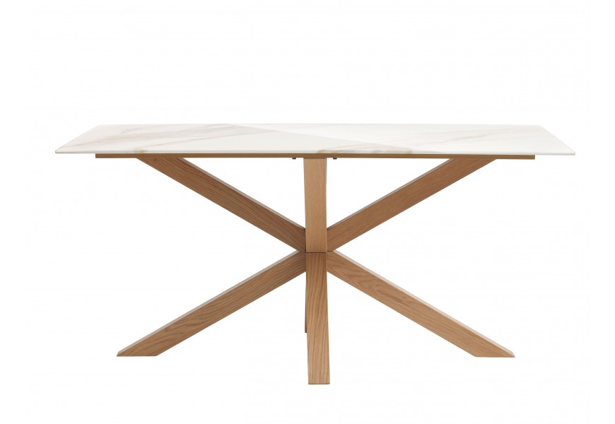 Skandinávský mramorový jídelní stůl Alina s obdélníkovou vrchní deskou z keramiky v bílé barvě s jemným hnědým a béžovým žilkováním s nohama s překříženým designem z dubového dřeva v přírodní světlé hnědé barvě