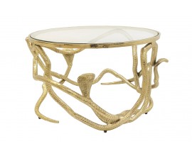 Designov&yacute; skleněn&yacute; art deco konferenčn&iacute; stolek Tierra Glam s kulatou transparentn&iacute; vrchn&iacute; deskou a podstavou z kovu ve zlat&eacute; barvě v atypick&eacute;m tvaru propleten&yacute;ch hadů se třemi vyčn&iacute;vaj&iacute;c&iacute;mi hlavami na stran&aacute;ch
