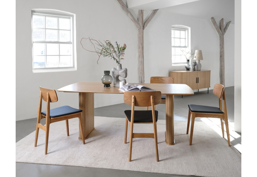 Retro moderní sestava nábytku do jídelny Bornholm ve světle hnědé barvě dubového dřeva s obdélníkovým jídelním stolem a oválným příborníkem s lamelovým dekorem s židlemi s černým koženým sedadlem
