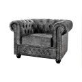 Designové klasické vintage sametové křeslo Chesterfield v šedé barvě s typickým diamantovým prošíváním s kulatými knoflíky s vyhnutou opěrkou s dekorativními vybíjenými nýty ve stříbrné barvě s vyřezávanými kulatými dřevěnými nožičkami