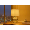 Modern&iacute; skleněn&aacute; stoln&iacute; lampa Glassy s asymetrickou transparentn&iacute; nohou a b&iacute;l&yacute;m textiln&iacute;m st&iacute;n&iacute;tkem 42 cm