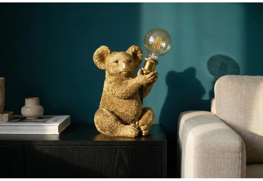 Designová zlatá art deco noční lampa Tierra Glam s motivem sedící koaly se zvednutými předními tlapkami držícími kulaté skleněné stínítko s hnědým tónováním