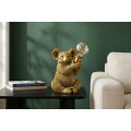 Designov&aacute; glamour stoln&iacute; lampa Tierra Glam ve zlat&eacute; barvě v podobě sed&iacute;c&iacute; koaly drž&iacute;c&iacute; kulat&eacute; skleněn&eacute; st&iacute;n&iacute;tko 34 cm