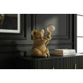 Designov&aacute; glamour stoln&iacute; lampa Tierra Glam ve zlat&eacute; barvě v podobě sed&iacute;c&iacute; koaly drž&iacute;c&iacute; kulat&eacute; skleněn&eacute; st&iacute;n&iacute;tko 34 cm