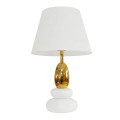 Moderní designová art deco bílá stolní lampa Caillou s akrylovou podstavou ve tvaru dvou na sobě uložených oblázků se zlatou zaoblenou nohou a textilním stínítkem válcovitého tvaru s rozšířenou spodní částí