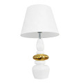 Designová glamour stolní lampa Caillou s bílou akrylovou nohou se zaobleným geometrickým tvarem s kompozicí na sobě uložených oblázků se zlatým detailem uprostřed s polohovatelným stínislem z bílého textilu a rozšířenou spodní stranou