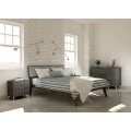 Moderní masivní postel Beliasso v tmavě šedé barvě na šikmých nožičkách s dřevěným podlouhlým čelem s textilním čalouněním ve světle šedé barvě s volitelnou barvou dřeva