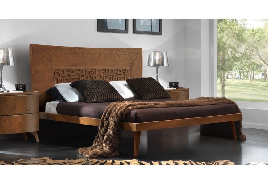 Masivní manželská italská postel Varietty v hnědé teplé barvě na nožičkách a rámem lemujícím matraci s ručně vyřezávaným čelem s reliéfem oblých čtverců v moderním stylu