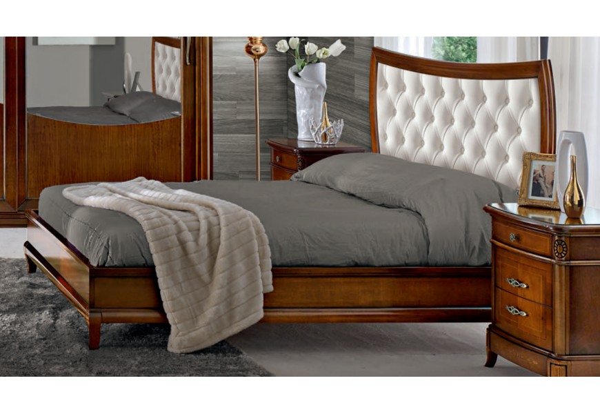 Klasická manželská postel Carpessio z masivního dřeva na oblých nožičkách s podlouhlým čelem a prošívaným čalouněním s chesterfield efektem