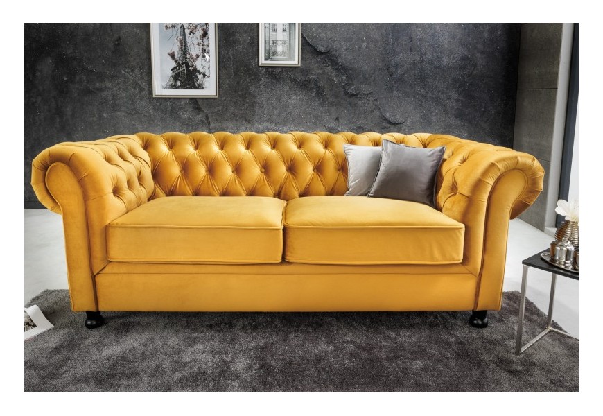 Designová chesterfield sedačka Milenna se sametovým potahem výrazné žluté barvy s černými nožičkami