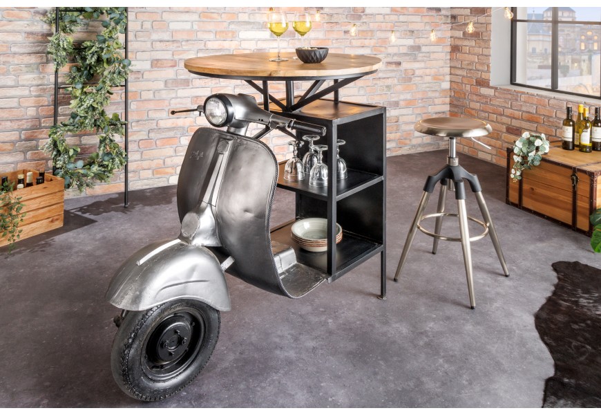Designový barový stůl Scooter s podstavou ve tvaru motorky ve stříbrné barvě s kulatou vrchní deskou z mangového dřeva a policemi s černou kovovou konstrukcí