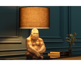 Art deco stolní lampa Apell s kovovou zlatou podstavou s designem sedící gorily as kulatým látkovým černým stínítkem