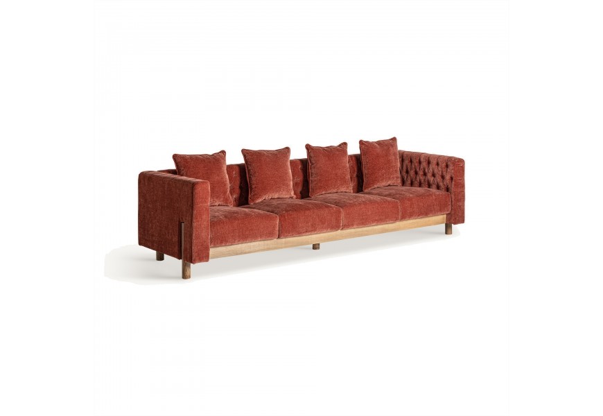 Luxusní čalouněná čtyřmístná sedačka Lenny v cihlové červené barvě s prošíváním na vnitřní straně opěrek as dřevěnými nožičkami v hnědé barvě v art deco stylu