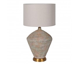 Designová vintage stolní lampa Tarragona s mohutnou podstavou z betonu ve světle béžové barvě s vyřezávaným geometrickým zdobením a patinou v odstínech červené a modré na zlatém kovovém podstavci s kulatým stínítkem ze lnu v naturální bílé krémové barvě