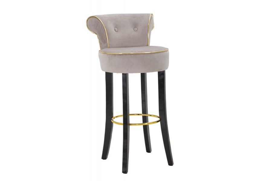 Designová glamour kulatá barová židle Vivienne s šedým semišovým potahem se zlatým lemováním s dekorativními knoflíky v zámeckém stylu s černými hranatými nožičkami s kovovou kulatou opěrkou na nohy ve zlaté barvě