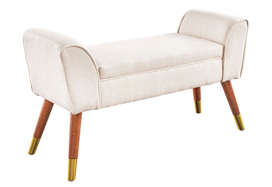 Art deco lavice Karen s béžovým sedadlem s textilním potahem v výraznou strukturou s opěrkami na ruce na bocích as nohama z hnědého masivního dřeva se zlatým zakončením