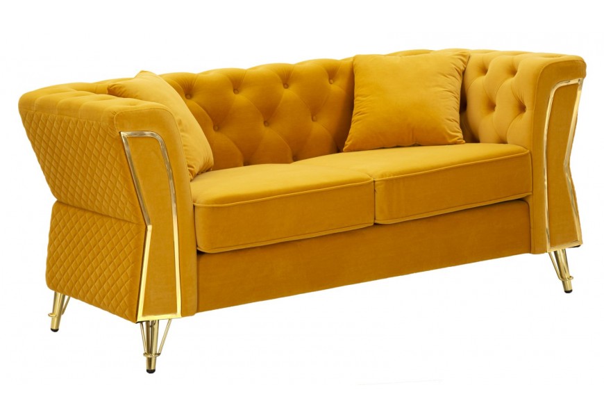 Designová art deco žlutá čalouněná dvousedačka Velaria s potahem ze sametu s dekorativním prošíváním na opěrce v chesterfield stylu a diamantovým vzorem na vnější straně se dvěma polštáři a dekorativním kovovým zlatým prvkem na opěrkách a šikmými nohami