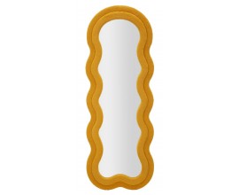Modern&iacute; n&aacute;stěnn&eacute; zrcadlo Swan v hořčicově oranžov&eacute; barvě s dvojit&yacute;m obloukov&yacute;m r&aacute;mem s boucl&eacute; potahem a asymetrick&yacute;m vlnit&yacute;m tvarem s d&yacute;hovanou zadn&iacute; stranou