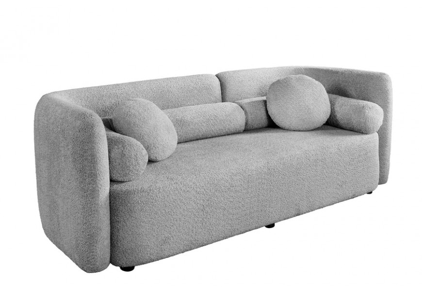 Art deco geometrická třímístná šedá bouclá sedačka Jina s oblým asymetrickým opěradlem a dvěma kulatými a válcovými polštáři na malých nožičkách
