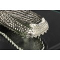 Glamour kulat&yacute; př&iacute;ručn&iacute; stolek Tierra Glam se stř&iacute;brn&yacute;m kovov&yacute;m drž&aacute;kem ve tvaru krokod&yacute;la a skleněnou deskou 61 cm