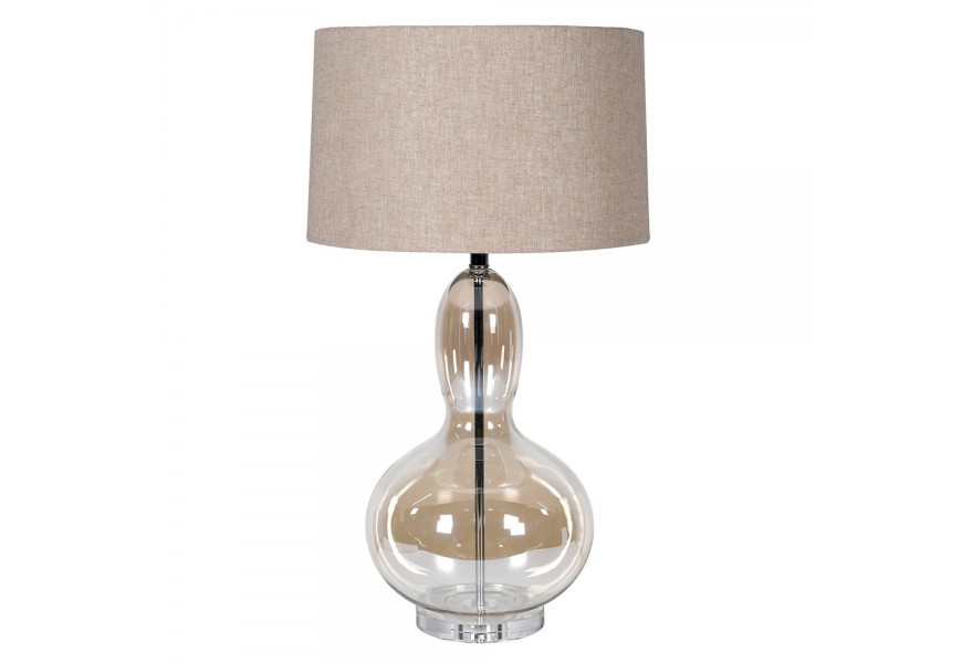 Designová glamour stolní lampa Kayla s nohou z průhledného skla s hnědým tónováním se zaoblenou siluetou ve tvaru hrušky s kulatým béžovým lněným stínítkem a kovovou konstrukcí v lesklém chromovém provedení