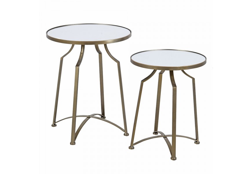 Designová zrcadlová glamour sada dvou příručních stolků Liven s kulatými vrchními deskami se čtyřmi prohnutými nožičkami s příčkou ve tvaru x z kovu ve zlaté barvě s patinou s matným povrchem