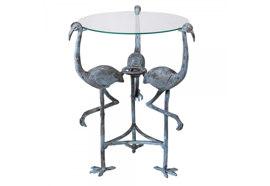 Designový příruční stolek Flamingo Blue v kulatém tvaru se skleněnou průhlednou deskou a kovovou podstavou ve tvaru tří plameňáků s modře šedou patinou