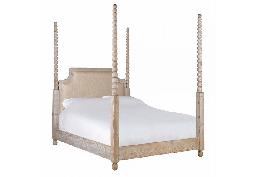 Luxusní venkovská masivní manželská postel Boia s rámem z recyklovaného dřeva ve světle hnědé barvě na nízkých kulatých nožičkách se čtyřmi vysokými sloupky s vyřezávaným designem kuliček a čelem s čalouněním ve světle béžové barvě