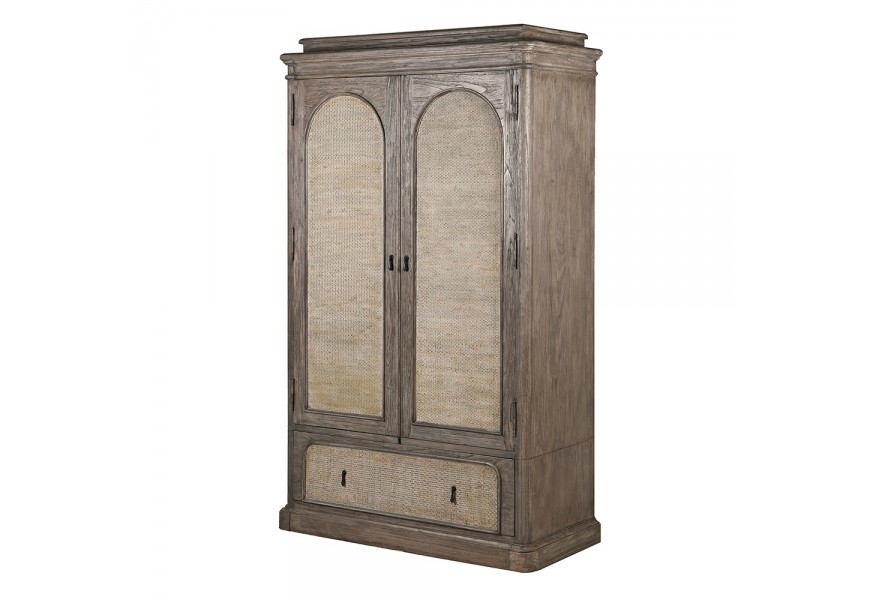Luxusní venkovská masivní šatní skříň Rickon s dvojitými dveřmi a šuplíkem s ratanovým výpletem s klenutým designem z masivního dřeva mindi v naturální hnědé barvě s šedou patinou